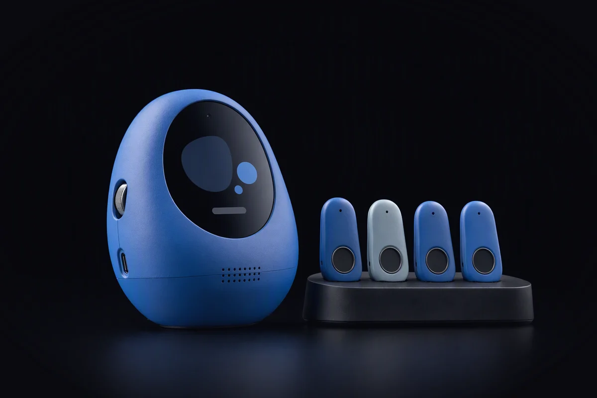 A pebble-shaped assistant on a kitchen shelf next to four small hardware keys on a rounded rack, one of them shorter and a lighter blue than the rest