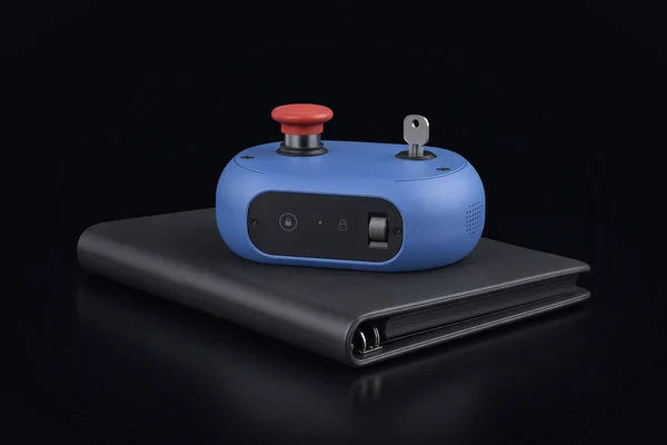 A safety interlock with a stop button and a key switch standing on a closed ring binder